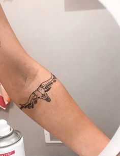 a person with a tattoo on their arm holding a spray bottle in front of a mirror