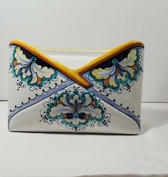 a white and blue ceramic box with yellow handles