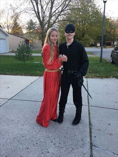 a man and woman dressed up in costume posing for a photo on the sidewalk together