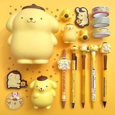 various stationery items are arranged on a yellow surface with stars and cartoon characters in the background