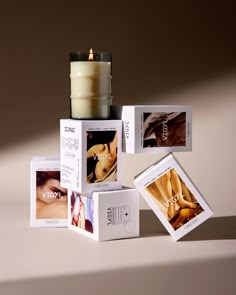 a candle is sitting on top of several boxes with pictures around it and the candles are lit