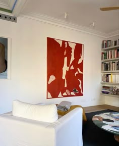 a living room filled with furniture and bookshelves next to a wall mounted painting