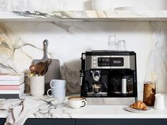 a coffee maker sitting on top of a counter next to some cups and saucers