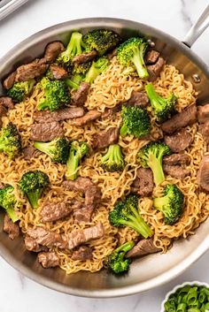 beef and broccoli stir fry in a skillet with chopsticks on the side