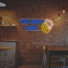 the man cave neon sign in front of a brick wall with bar stools next to it