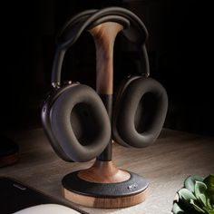 a pair of headphones sitting on top of a wooden stand next to a plant