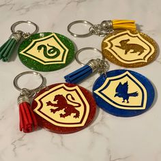 four harry potter inspired keychains on a marble countertop, one with a sly crest and the other with hogwart's