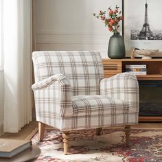 a plaid chair sitting on top of a rug in front of a table with flowers