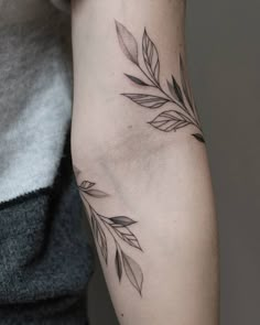 a woman's arm with leaves tattoo on the left side of her arm, which is black and white