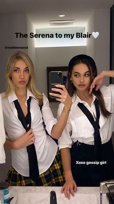 two beautiful young women standing next to each other in front of a mirror holding up their cell phones