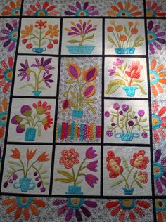 a quilted table top with flowers and vases on the same piece as it is being displayed