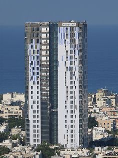 an aerial view of two tall buildings in front of the ocean and cityscape