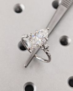 a white diamond ring sitting on top of a metal table next to a toothbrush