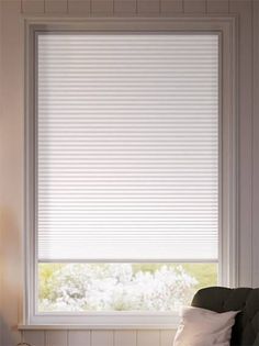 a chair sitting in front of a window with white blinds on top of the windowsill