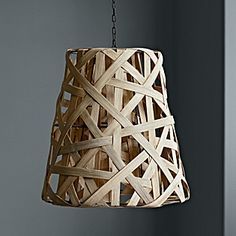 a wooden lamp hanging from a chain in a room with gray walls and flooring