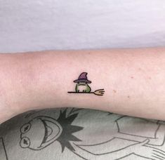 a small tattoo on the arm of a person wearing a hat and holding a knife