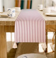 a striped table runner with tassels sits on top of a wooden dining table