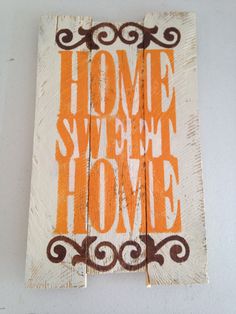 an orange and white sign that says home sweet home on it's wooden board