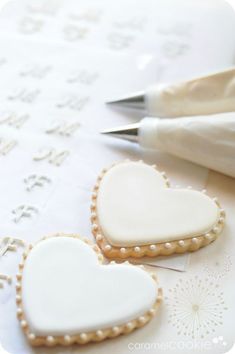 two heart shaped cookies sitting on top of a table next to a pair of scissors