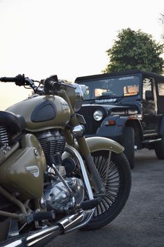 an army green motorcycle parked next to a jeep