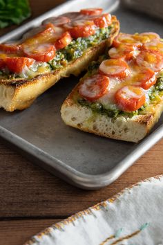 two pieces of bread with tomatoes and cheese on them sitting on a tray next to some parsley