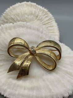 "Vintage Avon Gold tone Bow with Rhinestones. Brushed gold perfectly tied bow with rhinestone accents. Signed on back - AVON. In excellent vintage condition. 2.5 by 1.75\". Packaged for gifting!" Elegant Gold Bow For Formal Occasions, Gold Satin Bow For Wedding, Gold Ribbon Bow For Party, Elegant Gold Bow For Gifts, Elegant Gold Bow As Gift, Gold Party Bow With Ribbon, Elegant Gold Bow For Wedding, Vintage Jewelry With Decorative Bow For Formal Occasions, Elegant Gold Wedding Bow