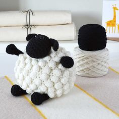 a crocheted sheep sitting on top of a table next to a ball of yarn