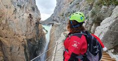 a person standing on a rope bridge with a view of a waterfall in the background