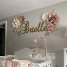 there is a crib with flowers on the wall and a name sign above it