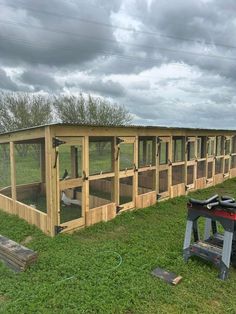 a large chicken coop in the middle of a field with chickens inside and on top of it