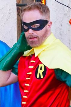 a man in a red shirt and green cape