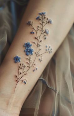 a woman's foot with blue flowers on the left side of her leg and an arm tattoo