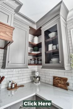 a kitchen with gray cabinets and white counter tops