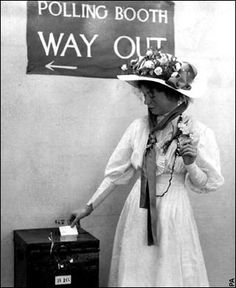 a woman in a dress and hat standing next to a sign