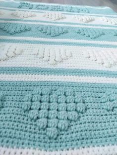 there is a crocheted blanket on the bed with blue and white stripes in it