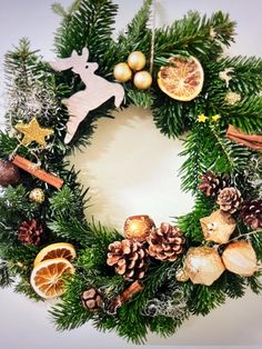 a christmas wreath with pine cones, oranges and other holiday decorations on white background