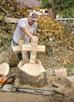 a man working on a wooden cross in the yard with chainsaws and tree trunks