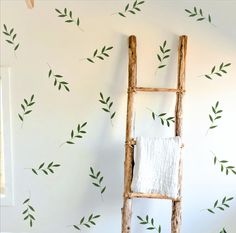 a ladder leaning against a wall with green leaves painted on the walls and behind it is a towel rack