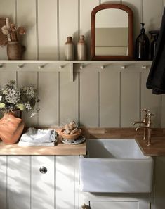 a white sink sitting under a mirror next to a wooden counter top in a kitchen