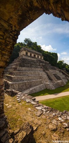 an ancient structure is seen through a hole in the stone wall that looks like it's built into the ground