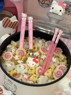 two hello kitty strawberries are in a cup with noodles and other food on the table