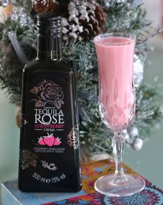 a bottle of tequila rose next to a glass filled with pink liquid and pine cones