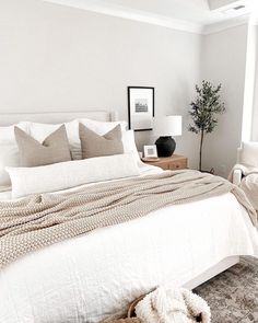 a bedroom with white walls and neutral bedding