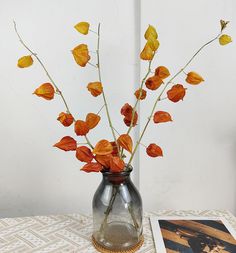 a vase filled with orange flowers sitting on top of a table next to a photo