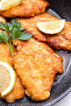 fried fish with lemons and parsley on a black plate, ready to be eaten