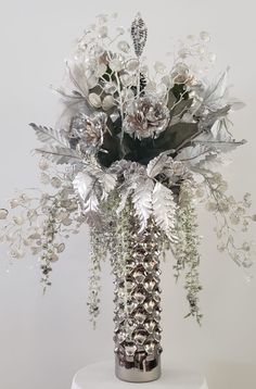 a silver vase filled with flowers on top of a white table