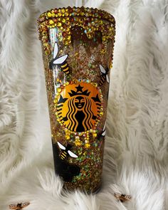 a starbucks cup is decorated with gold and black glitters, bees, and honeybees