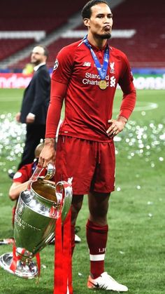 the soccer player is holding his trophy and looking at the camera while standing on the field