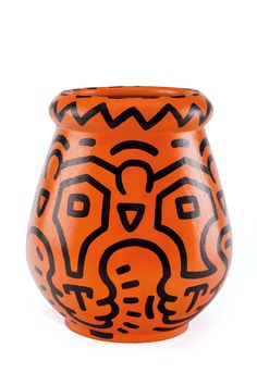 an orange vase with black designs on it