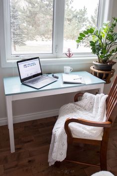 a laptop computer sitting on top of a wooden desk next to a potted plant